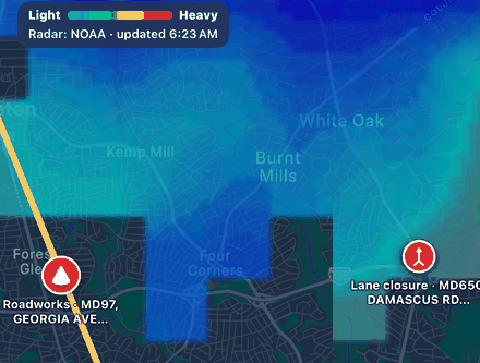 Rain radar from NOAA over Washington, DC suburbs, with a colour scale from light to heavy, updated 6:23 AM, and two Maryland road reports on the map.