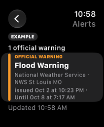 The alerts list on Apple Watch, marked EXAMPLE: the Flood Warning from NWS St Louis MO, issued Oct 2 at 10:23 PM, until Oct 8 at 7:17 AM.